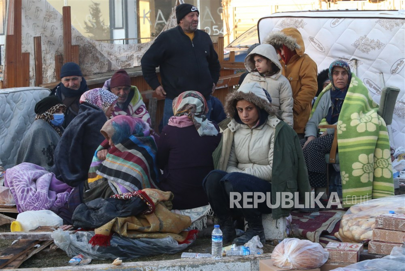 Orang-orang menunggu di lokasi bangunan yang runtuh di kota Adiyaman, tenggara Turki, Rabu (8/2/2023). 