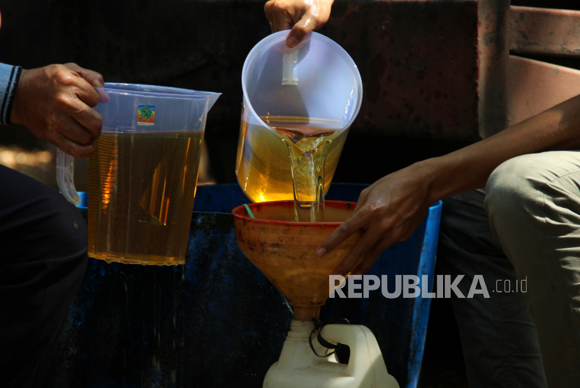 Dua pekerja menuangkan minyak goreng ke wadah milik warga (ilustrasi). PT Rajawali Nusindo telah mendistribusikan sebanyak lebih dari 7,2 juta liter minyak goreng.