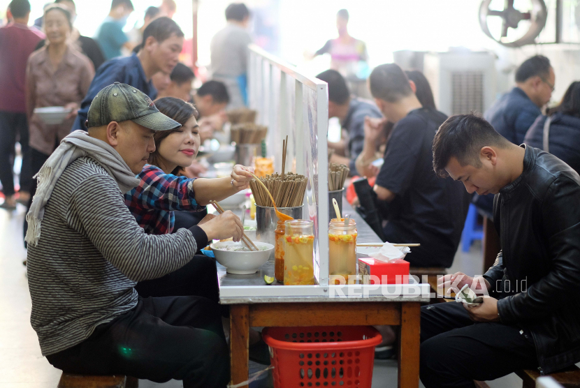 Sejumlah orang menikmati Pho atau sup mie yang dipisahkan oleh dinding plastik transparan, di sebuah restoran di Hanoi, Vietnam. Kedutaan Besar Republik Indonesia (KBRI) di Hanoi, Vietnam, berencana kembali memulangkan warga negara Indonesia yang tertahan di negara itu pada awal Juli 2020.