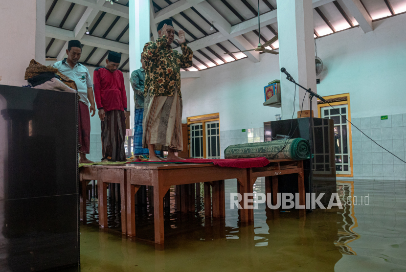 Sejumlah warga melaksankan Shalat Asar berjamaah di atas meja yang diletakkan di lantai Masjid Jami Al Muttaqin yang terendam banjir di Desa Prampelan, Kecamatan Sayung, Kabupaten Demak, Jawa Tengah, Selasa, (3/1/2023). Warga setempat memanfaatkan meja untuk saf shalat berkapasitas terbatas karena banjir merendam lantai masjid tersebut dengan ketinggian bervariasi antara 10-30 cm akibat intensitas hujan tinggi sejak Sabtu (31/12/2022) dini hari. Sebagian Wilayah Jateng Selatan Lewati Puncak Musim Hujan