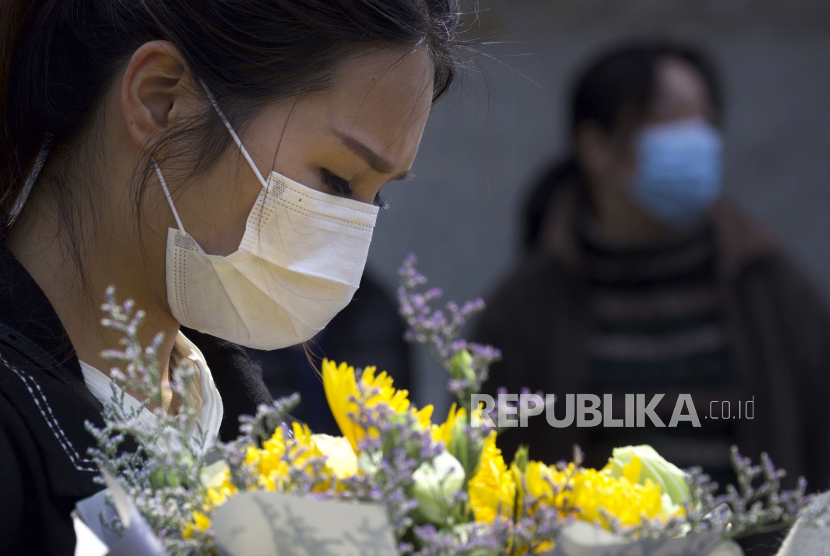 Warga membawa bunga saat hari berkabung nasional untuk para korban Covid-19 di Wuhan, Provinsi Hubei, China, Sabtu (4/4). China mengadakan hari berkabung nasional bagi orang-orang yang meninggal selama wabah virus corona dan COVID-19