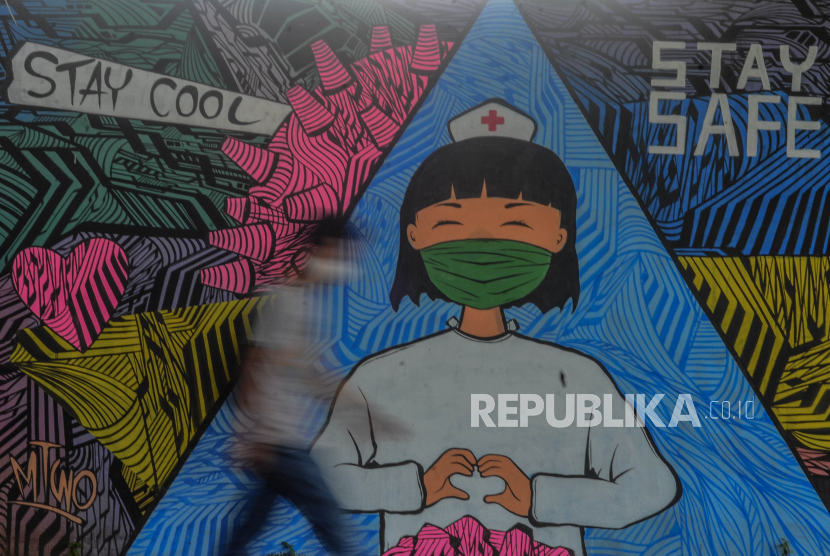 Warga melintas di depan mural tentang pandemi virus corona atau COVID-19 di Kabupaten Ciamis, Jawa Barat, Jumat (10/4/2020). Mural yang dibuat oleh warga setempat ditujukan sebagai bentuk keprihatinan atas merebaknya COVID-19 serta sebagai dukungan kepada tenaga medis yang menjadi garda terdepan dalam menghadapi pandemi tersebut