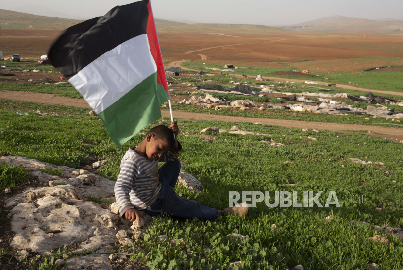  Seorang bocah lelaki Badui Palestina memegang bendera Palestina setelah pasukan Israel menghancurkan tenda dan bangunan lain di dusun Khirbet Humsu di Lembah Jordan di Tepi Barat, Rabu, 3 Februari 2021. 
