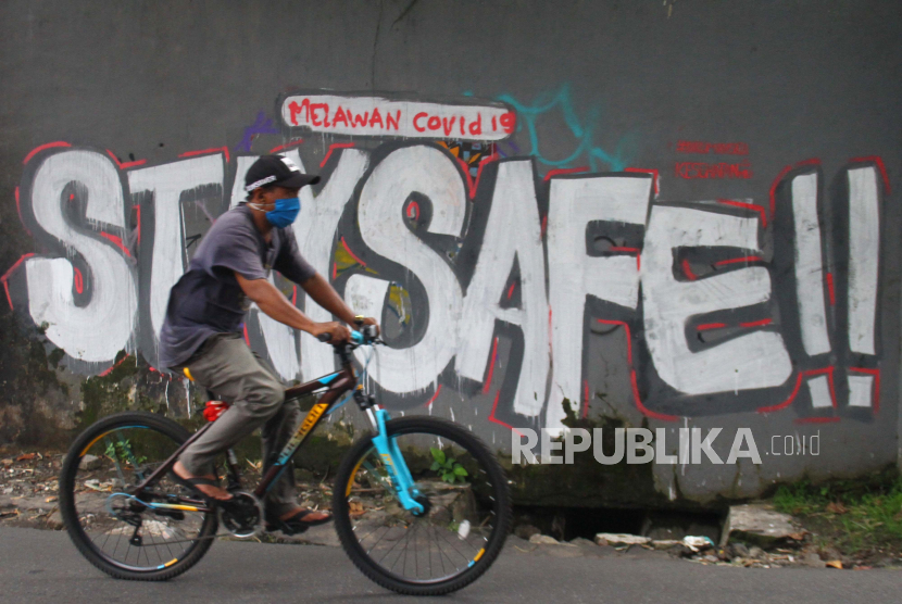 Pengendara sepeda melintas di depan mural sosialisasi Covid-19 saat di Jalan Sudimoro, Malang, Jawa Timur. (ilustrasi)