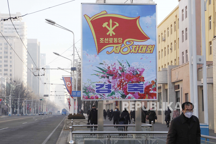 Orang-orang berjalan melewati papan reklame yang mengumumkan Kongres ke-8 Partai Buruh di sepanjang jalan utama Distrik Pusat di Pyongyang, Korea Utara, pada Rabu, 6 Januari 2021. 