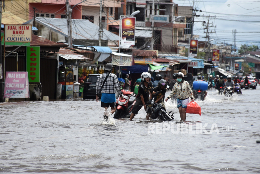 Sejumlah pengendara motor dan warga berjalan melintasi banjir di Kalimantan Barat (ilustrasi). Hingga kini ada 138 desa terdampak banjir di Kalbar.