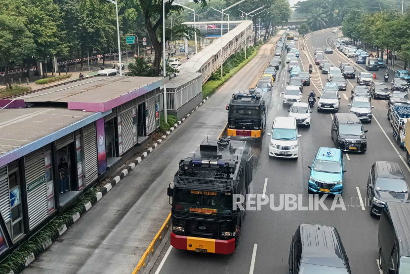 Mobil kepolisian menyemprotkan air di Jalan Jenderal Sudirman, Jakarta, Rabu (23/8/2023). Penyemprotan di sekitar jalan protokol tersebut sebagai upaya untuk membersihkan debu-debu yang bertebaran di jalanan akibat polusi udara.