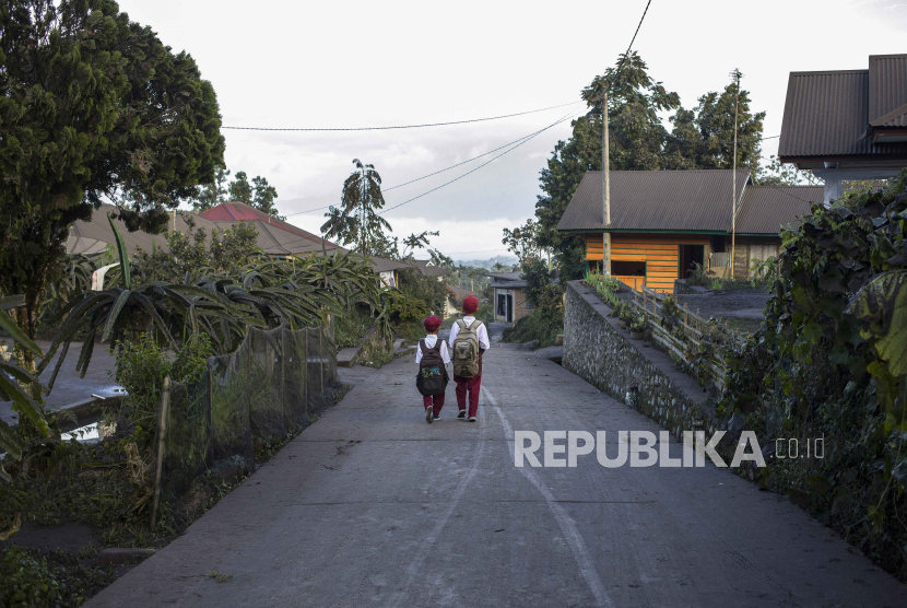 Siswa berjalan menuju sekolahnya saat abu vulkanik letusan Gunung Marapi menutupi jalan di Agam, Sumatera Barat,  Selasa (5/12/2023).