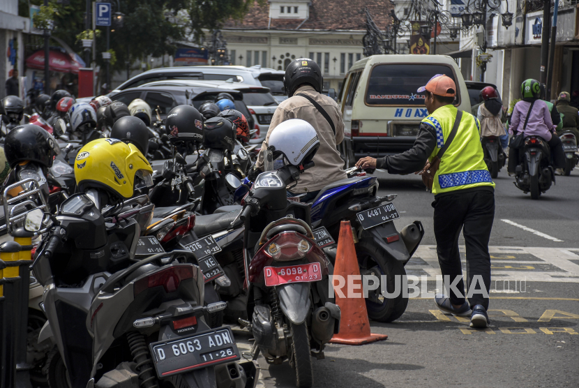 Juru parkir membantu pengendara yang akan parkir di Jalan Braga, Kota Bandung.