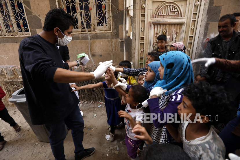 Seorang relawan (kiri) membagikan masker saat kegiatan pensterilan daerah kumuh dari penyebaran virus Corona (COVID-19) di Sanaa, Yaman, Senin (30/3). Relawan Yaman berinisiatif untuk mensterilkan daerah kumuh di Sanaa dan membantu orang kurang mampu untuk melindungi diri mereka sendiri dan meningkatkan kesadaran mereka tentang SARS-CoV-2 virus Corona yang menyebabkan penyakit COVID-19