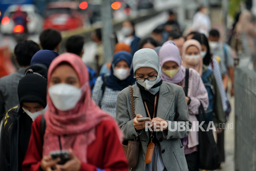 Pekerja melintas di pelican crossing di kawasan Perkantoran Sudirman, Jakarta, Rabu (26/4/2023).