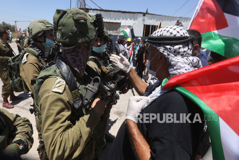 Para pengunjukrasa Palestina mengibarkan bendera Palestina.