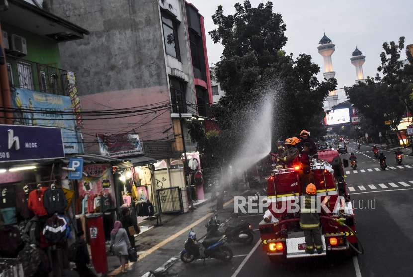 Petugas dari Dinas Pemadam Kebakaran dan Penanggulangan Bencana (Diskar PB) Kota Bandung menyemprotkan cairan disinfektan di ruas Jalan Dalem Kaum, Kota Bandung, Senin (23/3). 