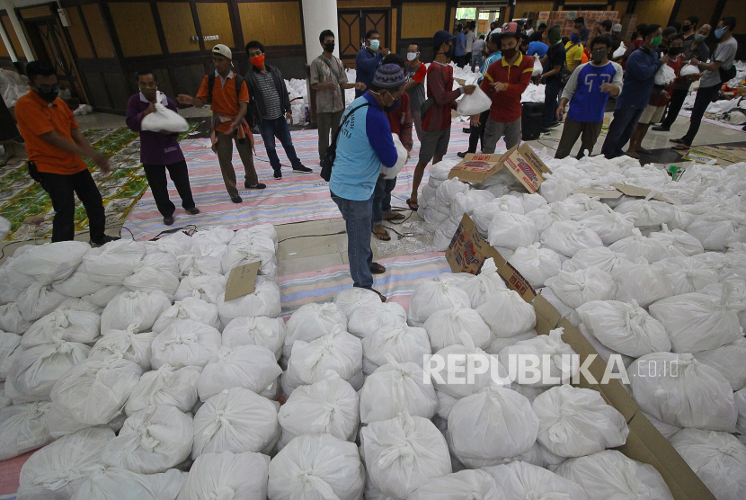 Relawan bergotong royong mengangkat paket sembako bantuan dari berbagai perusahaan di Convention Hall, Surabaya, Jawa Timur, Ahad (26/4/2020). Bantuan sembako sebanyak 68