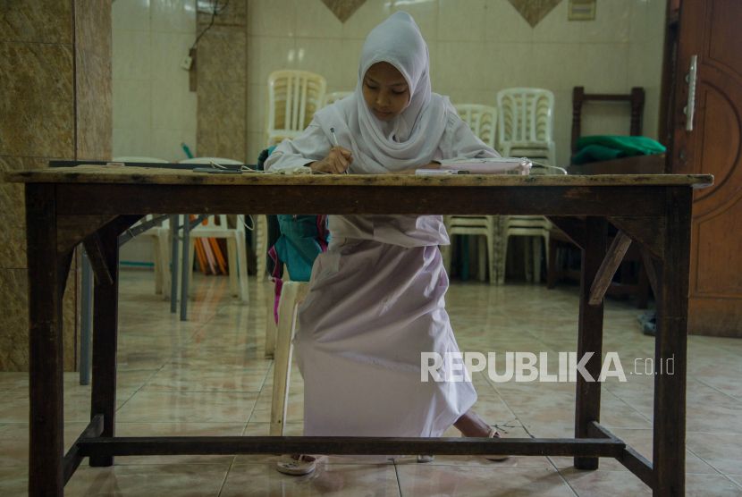 Siswa mengerjakan soal penilaian akhir semester (PAS) tahun ajaran 2020/2021 menggunakan layanan Jakwifi di posyandu kawasan Kelurahan Galur, Jakarta, Senin (30/11). Mulai Januari 2021, sekolah tatap muka akan diizinkan kembali dengan syarat ketat. IDAI memandang sekolah tatap muka berisiko tinggi karena laju Covid-19 yang belum terkendali.