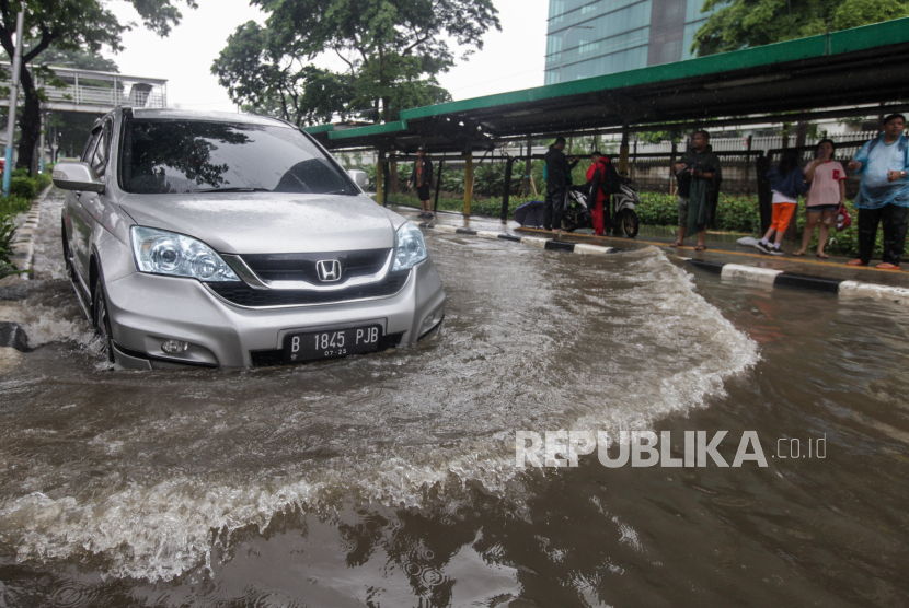 Mobil melintasi genangan air di Jalan Letjen Suprapto, Cempaka Putih, Jakarta, Kamis (29/2/2024). Hujan deras yang mengguyur Jakarta sejak dini hari dan buruknya drainase membuat ruas jalur lambat pada jalan tersebut tergenang air.