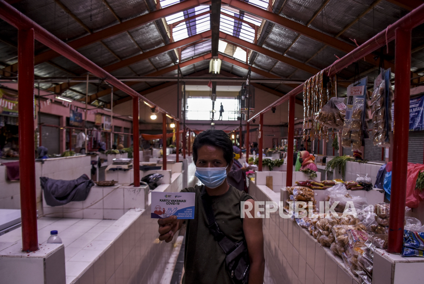 Pedagang menunjukkan kartu vaksinasi Covid-19 usai disuntik vaksin Covid-19 Sinovac di Pasar Melong, Kota Cimahi, Rabu (24/2). Sedikitnya 95 pedagang Pasar Melong menerima vaksin Covid-19 Sinovac dosis pertama pada pelaksanaan vaksinasi tahap kedua di Jawa Barat yang ditujukan bagi lansia dan petugas publik seperti aparatur sipil negara (ASN), anggota TNI dan Polri, pedagang pasar, pekerja seni, pekerja pariwisata dan sejenisnya. Foto: Abdan Syakura/Republika