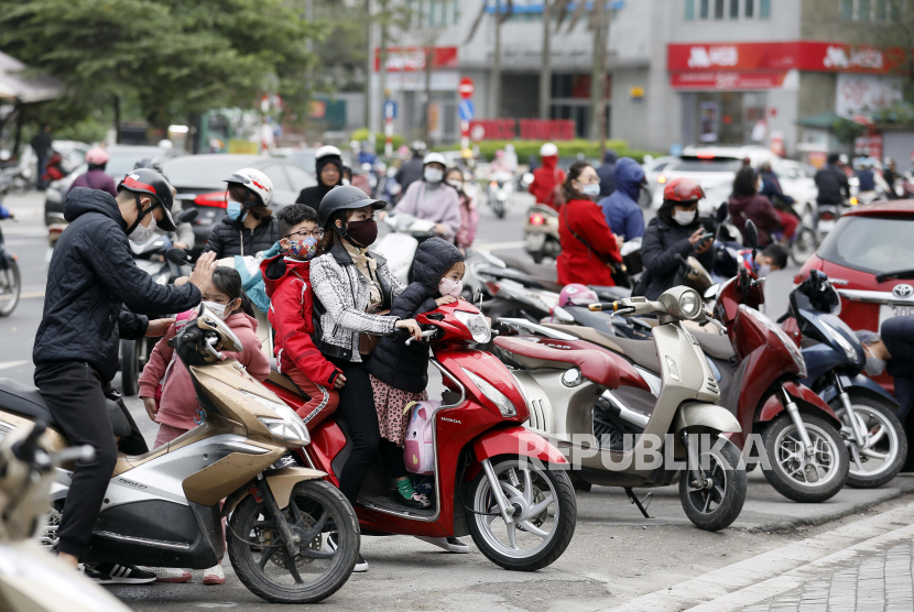 Vietnam Targetkan Bangun 5.000 Km Jalan Tol pada 2030. Para orang tua mengantar anak-anak mereka ke sekolah dengan sepeda motor di Hanoi, Vietnam, 02 Maret 2021.