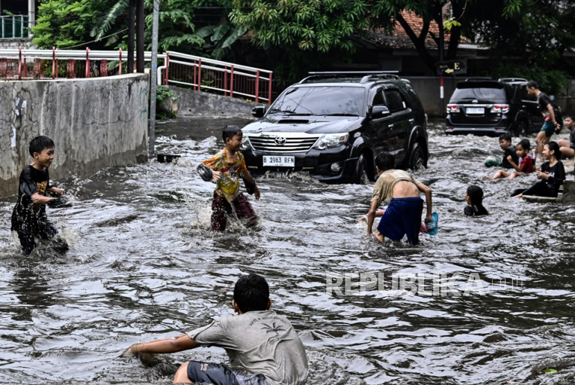 Anak-anak bermain saat banjir di Komplek Polri Pondok Karya, Mampang Prapatan, Jakarta (8/12/2023). Menurut warga, kawasan tersebut rutin tergenang banjir akibat luapan air dari aliran Kali Krukut. 