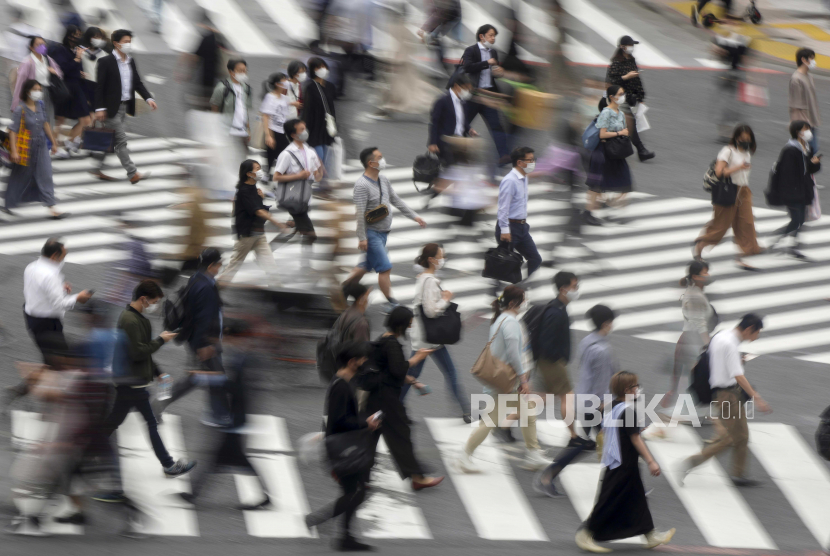 Pejalan kaki berjalan di sepanjang persimpangan Shibuya berebut di Tokyo, Jepang. 