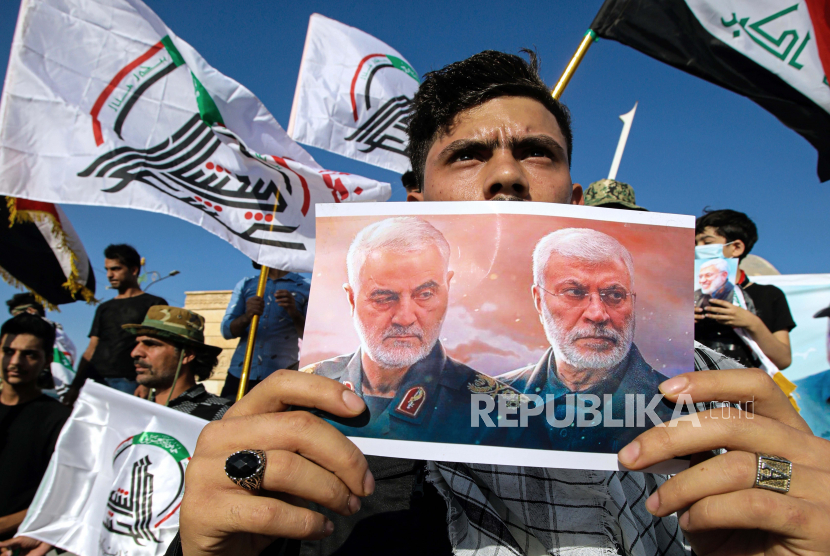  Seorang pendukung milisi yang didukung Iran memegang poster Jenderal Iran Qassem Soleimani. Soleimani merupakan tokoh militer Iran yang memiliki pengaruh besar di Timur Tengah.