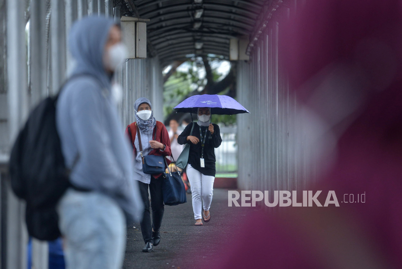 Warga dengan mengunakan payung menerjang hujan di kawasan Jalan  Gatot Subroto, Jakarta, Jumat (9/12/2022). Pengamat transportasi Deddy Herlambang menanggapi petisi kembalikan Work From Home (WFH) di Jakarta yang viral di media sosial.