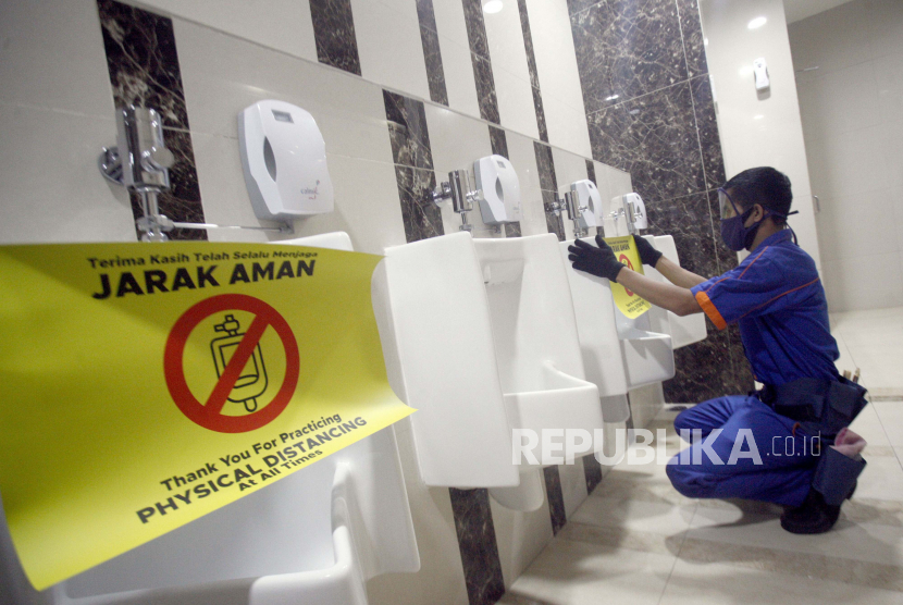 Pekerja memasang stiker tanda jaga  jarak di toilet pusat perbelanjaan/mal. (Ilustrasi)