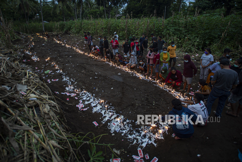 Sejumlah warga menyalakan lilin saat berziarah di tempat pemakaman massal korban tanah longsor di Desa Nelelamadike, Kecamatan Ile Boleng, Kabupaten Flores Timur, Nusa Tenggara Timur (NTT), Rabu (7/4/2021). Sebagian besar dari 55 orang korban meninggal akibat tanah longsor di desa tersebut dimakamkan di lokasi tersebut. 