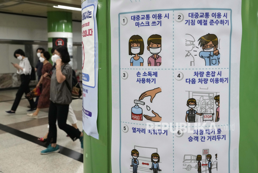 Orang-orang yang memakai masker melewati poster tentang tindakan pencegahan terhadap virus corona di stasiun kereta bawah tanah di Seoul, Korea Selatan, Selasa, 13 Juli 2021.