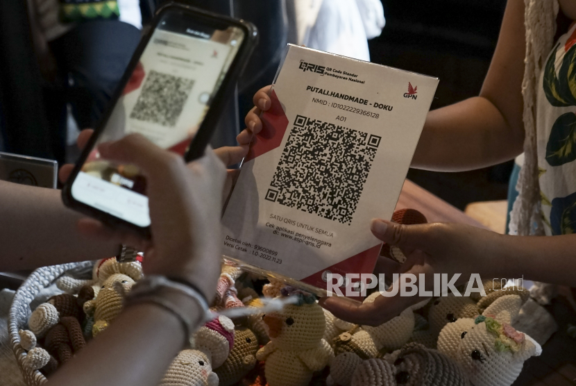 Pengunjung melakukan pembayaran menggunakan fitur scan QRIS saat acara bazar Palawan Pasar Pasaran di Ubud, Gianyar, Bali, Sabtu (26/11/2022). Tarif QRIS tak Ganggu Target onboarding digital UMKM.