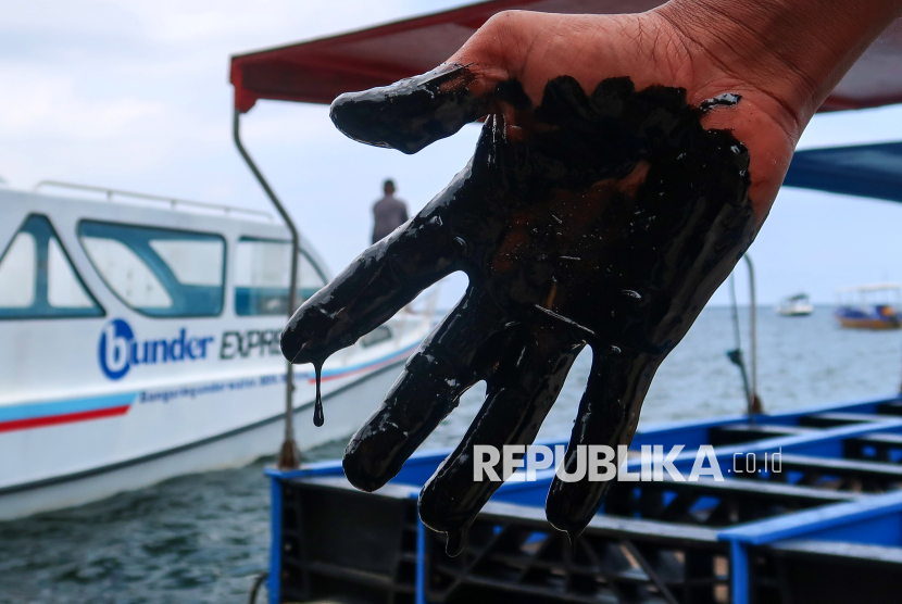 Pengelola menunjukan telapak tanganya yang terkena tumpahan oli di Pantai Bangsring, Banyuwangi, Jawa Timur, Rabu (19/2/2025). Sudah 3 hari tumpahan oli yang tidak diketahui sumber nya itu mencemari Pantai Bangsring yang menjadi tempat wisata dan zona konservasi terumbu karang seluas 15 hektare sehingga mengancam ke berlangsungan hidup biota laut. 