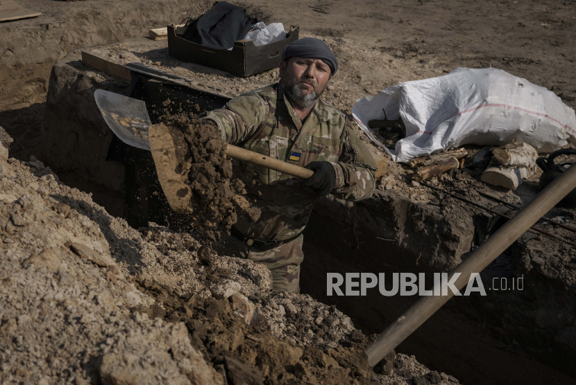  Seorang prajurit Ukraina menggali parit di posisi utara ibukota Kyiv, Ukraina, Selasa, 29 Maret 2022. Pasukan Rusia membombardir pinggiran Kiev dan kota yang terkepung di Ukraina utara pada Rabu (30/3/2022). 