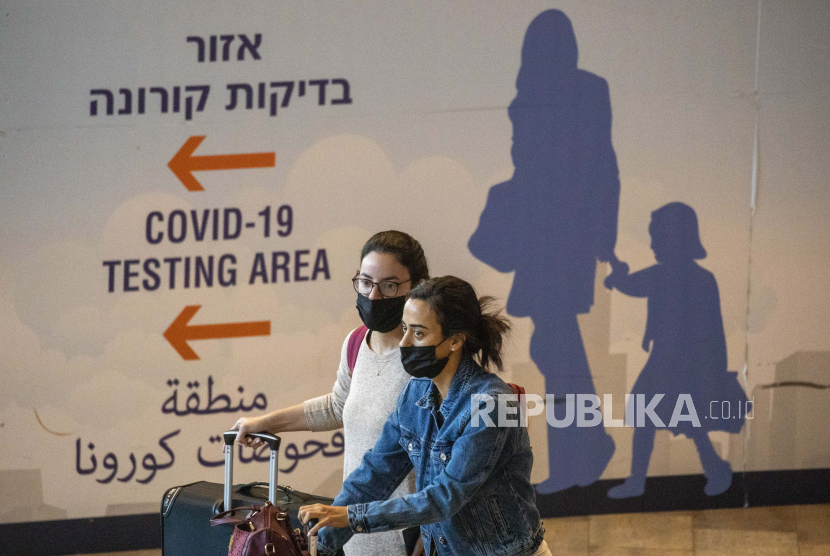  Pelancong yang memakai masker pelindung tiba di Bandara Ben Gurion dekat Tel Aviv, Israel, Ahad, 28 November 2021. Israel pada Ahad menyetujui larangan masuk ke warga negara asing dan penggunaan teknologi kontroversial untuk pelacakan kontak sebagai bagian dari upayanya untuk menekan pada varian virus corona baru.