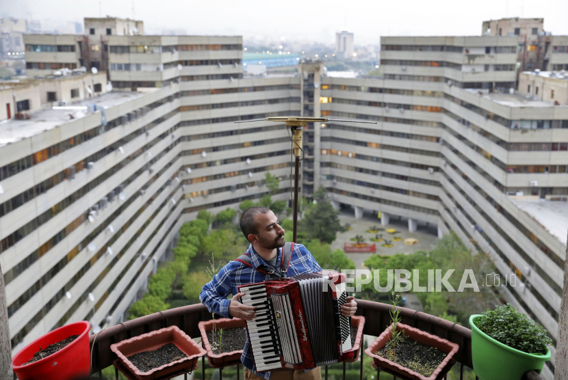 Musisi Behnam Emran (28)  bermain akordeon di atap rumahnya selama isolasi karena pandemi corona di Teheran, Iran, Rabu (8/4). Dengan gedung petunjukan yang ditutup dan banyak warga berada dirumah karena wabah virus terburuk di Timur Tengah