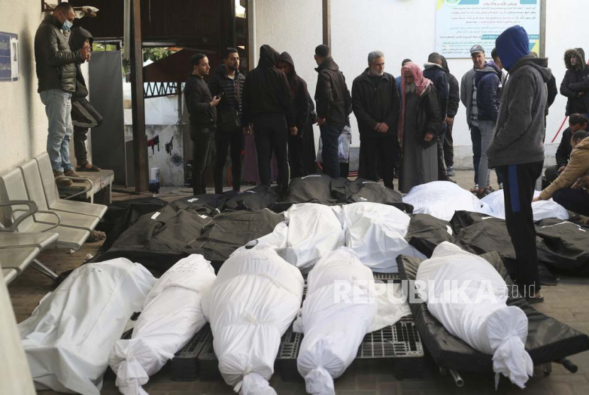 Warga Palestina berdiri di sekitar kerabat mereka yang tewas dalam pemboman Israel di Jalur Gaza di kamar mayat di Rafah, Rabu, (21/2/2024).