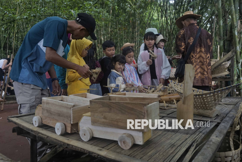 Wisatawan memilih mainan tradisional yang dijual di lokasi wisata Pasar Papringan Ngadiprono, Kedu, Temanggung, Jawa Tengah, Ahad (12/1/2025). Pasar Papringan Ngadiprono merupakan destinasi wisata alternatif dengan konsep wisata budaya, konservasi alam, kuliner dan pendidikan yang transaksinya menggunakan mata uang Pring (bambu) sebagai upaya meningkatkan perekonomian warga setempat. 