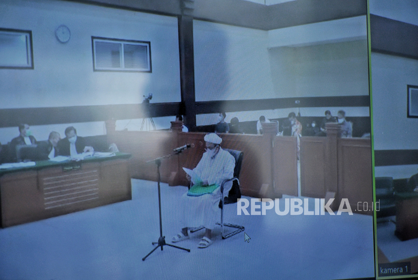 Layar yang menampilkan suasana sidang lanjutan kasus pelanggaran protokol kesehatan dengan terdakwa mantan Pemimpin Front Pembela Islam Rizieq Shihab yang digelar secara virtual di Pengadilan Negeri Jakarta Timur, Jumat (25/3). Hakim mengabulkan permohinan Rizieq shihab untuk hadir langsung dalam sidang yang beragendakan pembacaan eksepsi. Republika/Thoudy Badai
