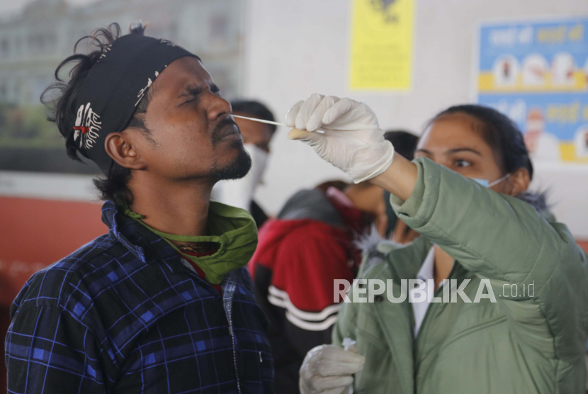  Seorang petugas kesehatan mengambil sampel swab penumpang yang memasuki kota untuk tes COVID-19 di stasiun kereta api di Ahmedabad, India, Jumat, 3 Desember 2021. Pakar kesehatan India ingatkan pentingnya masker di tengah merebaknya Omicron. Ilustrasi.