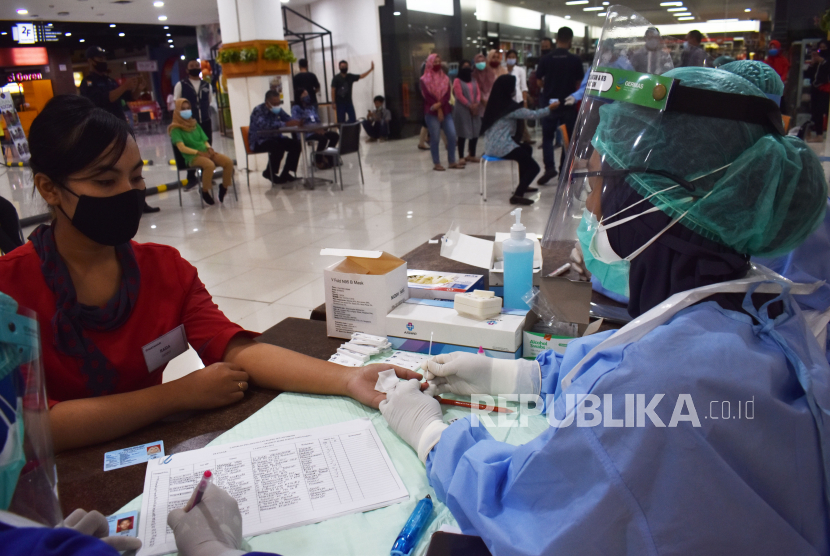 Petugas kesehatan mengambil sampel darah pekerja saat tes diagnostik cepat (rapid test) COVID-19 secara massal di sebuah plaza Kota Madiun, Jawa Timur, Selasa (5/1/2021). Pemkot Madiun memfasilitasi rapid test bagi seluruh pekerja di pusat perbelanjaan terbesar di kota tersebut guna mencegah penularan COVID-19 menyusul meningkatnya kasus terkonfirmasi positif COVID-19 secara nasional. 