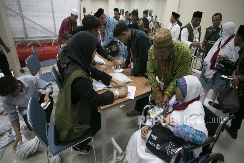 Petugas membantu jamaah calon haji untuk mengambil gelang identitas saat memasuki Asrama Haji Embarkasi Kertajati, Indramayu, Jawa Barat, Sabtu (27/5/2023).