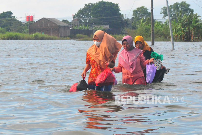 Warga melintasi jalan yang terendam banjir di Karangturi, Setrokalangan, Kaliwungu, Kudus, Jawa Tengah. Kemenko PMK sebut anggaran dana desa sudah bisa digunakan untuk menangani bencana.