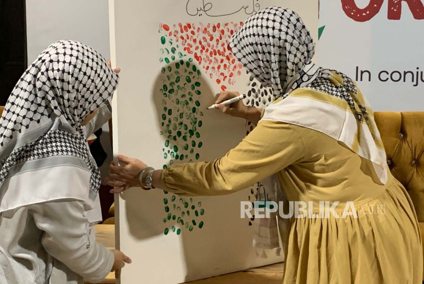 Direktur Utama Adara, Maryam Rachmayani, menandatangani kanvas bergambar bendera Palestina dalam acara Women Speak Up For Palestine di Aljazeerah Restaurant, Jakarta, Sabtu (25/11/2023). 