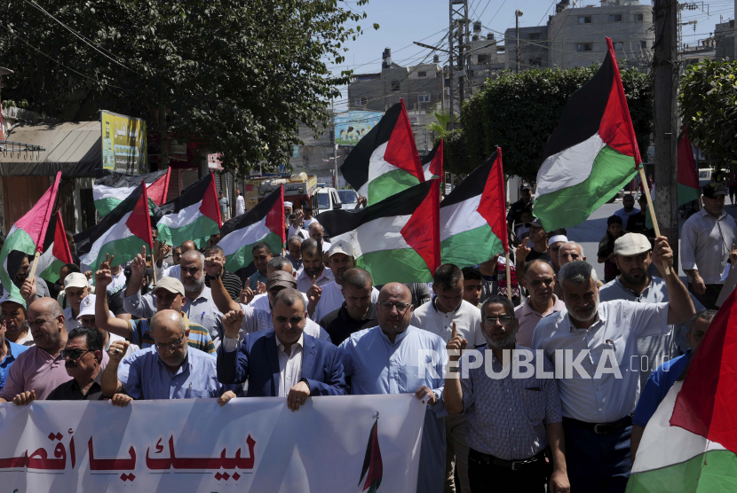 Warga Palestina berbaris sambil mengibarkan bendera nasional mereka selama unjuk rasa solidaritas dengan Al-Quds, atau Yerusalem, di jalan utama di Khan Younis, Jalur Gaza selatan, Jumat, 9 September 2022. Populasi Gaza Lampaui 2,3 Juta Jiwa