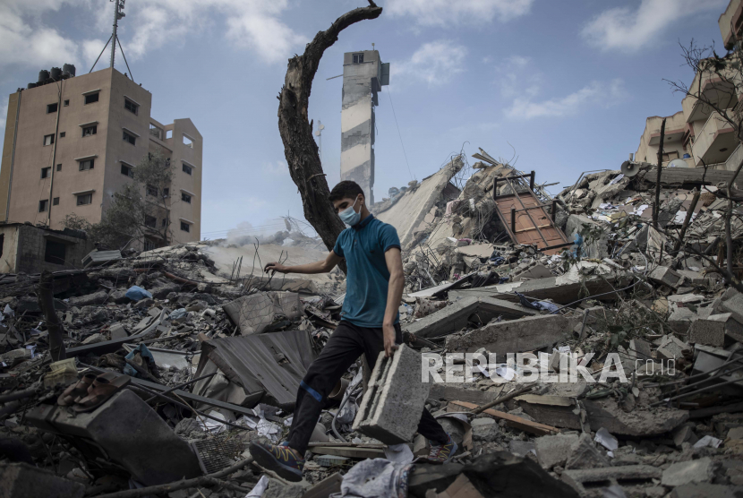 Seorang Palestina memeriksa kerusakan gedung berlantai enam yang dihancurkan bom Israel di Kota Gaza, Selasa (18/5).