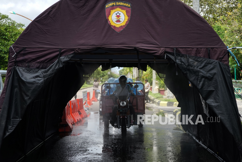 Pengendara kendaraan bermotor melintasi bilik tenda disinfektan di kawasan kota Palangkaraya, Kalimantan Tengah. (ilustrasi)