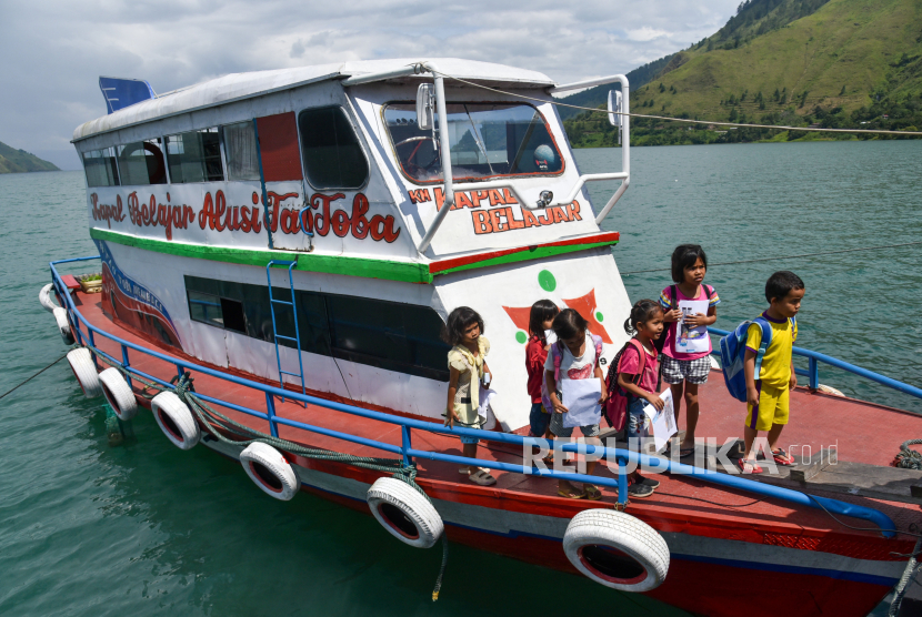 Sejumlah anak meninggalkan kapal usaimengikuti kegiatan belajar di atas kapal belajar Alusi Tao Toba di Dermaga Desa Simangulampe, Humbang Hasundutan, Sumatera Utara, Senin (11/12/2023). Kapal belajar yang digunakan sejak tahun 2015 itu memiliki koleksi buku sebanyak 1.000 buku, berkeliling ke tujuh kabupaten di seputaran Danau Toba guna mencerdaskan anak dan menjaga minat baca sejak usia dini.  