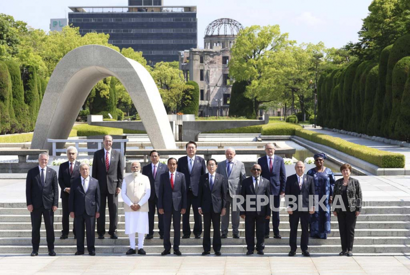  Perdana Menteri Jepang Fumio Kishida (tengah) dan para pemimpin dari negara tamu undangan berpose untuk foto, setelah meletakkan bunga di Cenotaph untuk Korban Bom Atom, di Peace Memorial Park di Hiroshima, Jepang barat, di sela-sela Rombongan Pertemuan Tujuh Negara (G7), Ahad (21/5/2023)  Para pemimpin dari negara tamu undangan, dari kiri ke kanan, Sekretaris Jenderal Organisasi untuk Kerja Sama dan Pembangunan Ekonomi (OECD) Mathias Cormann, Direktur Eksekutif Energi Internasional Agency Fatih Birol, Sekretaris Jenderal PBB Antonio Guterres, Presiden Bank Dunia David Malpass, Perdana Menteri India Narendra Modi, Perdana Menteri Vietnam Pham Minh Chinh, Presiden Indonesia Joko Widodo, Presiden Korea Selatan Yoon Suk Yeol, Perdana Menteri Jepang Kishida, Presiden Brazil Luiz Inacio Lula de Silva, Presiden Komoro Azali Assoumani, Perdana Menteri Australia Anthony Albanese, Perdana Menteri Kepulauan Cook Mark Brown, Direktur Jenderal Organisasi Perdagangan Dunia (WTO) Ngozi Okonjo-Iweala, dan Direktur Pelaksana Dana Moneter Internasional (IMF) Kristalina Georgieva .