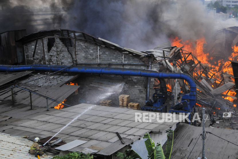 Petugas mencoba memadamkan kebakaran di pabrik mebel di kawasan Cakung, Jakarta Timur, Ahad (9/8/2020). Penyebab kebakaran yang terjadi pada pukul 12.06 WIB tersebut masih dalam penyelidikan petugas. 