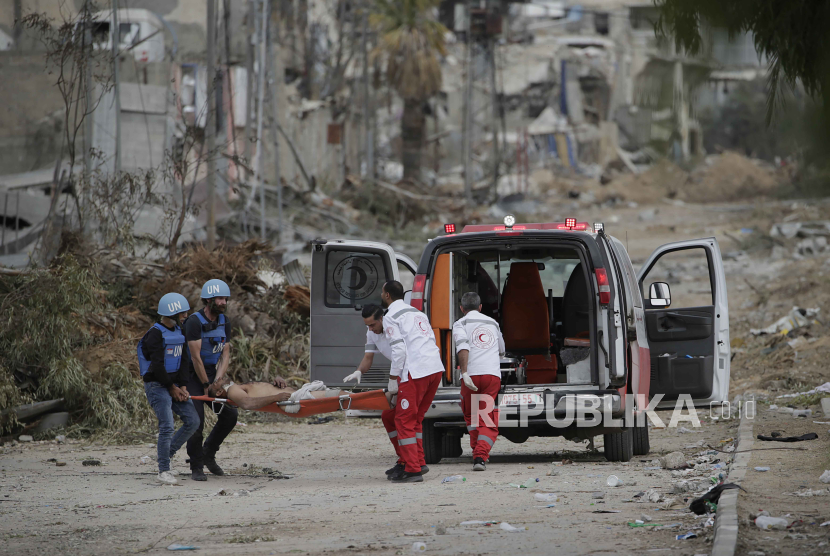 Pekerja PBB dan Bulan Sabit Merah mencoba membantu seorang pria terluka tembak saat kembali dari selatan ke utara Jalur Gaza, 25 November 2023.