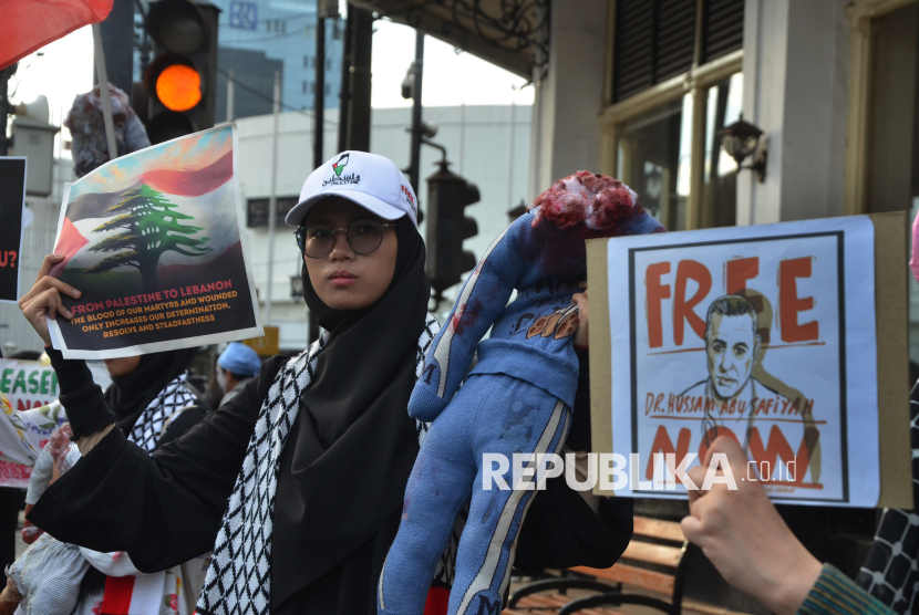 Sejumlah massa memperlihatkan poster kepada pengendara saat aksi solidaritas Palestina bertajuk Silent March Global Solidarity for Palestina bersama Solidaritas Seni untuk Palestina dan Bandung Spirit for Palestina, di Jalan Asia Afrika, Kota Bandung, Rabu (1/1/2025). Aksi tersebut diantaranya menuntut stop genosida dan mendesak dibebaskannya Direktur RS Kamal Adwan Dr Hussam Abu Syifa, Staff dan semua pasien. Hal tersebut terkait penyerbuan RS Kamal Adwan oleh militer Israel.